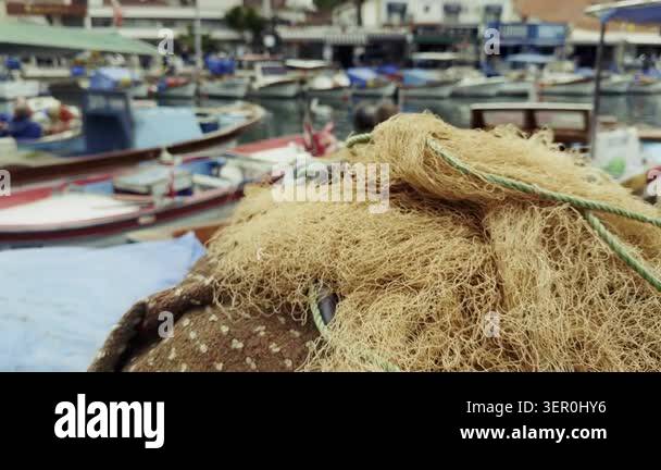 High resolution cinematic shot of traditional fishing nets stacked on a ...