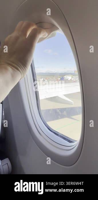 Hand opening and closing airplane window shade during flight, passenger ...