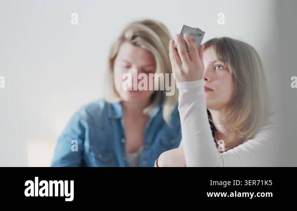 Young woman learning makeup application from her mother while using a ...