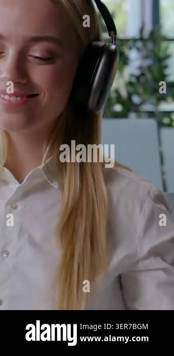 Happy Caucasian business woman in headphones listening music dancing ...