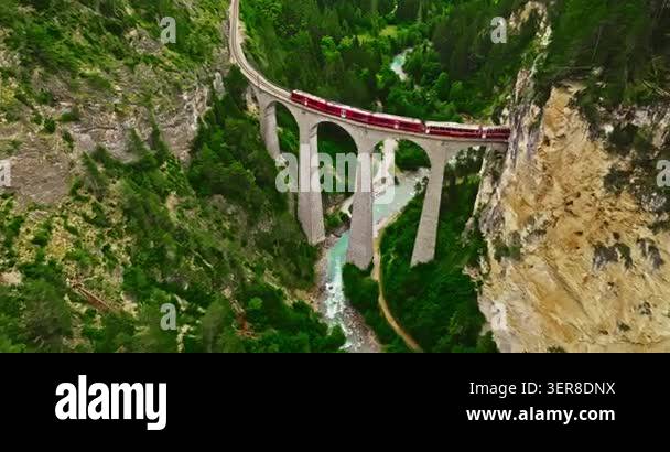 Aerial video of the red train traversing the Landwasser viaduct. The ...