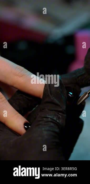 Close-up of nail technician refining the shape of a finished manicure ...