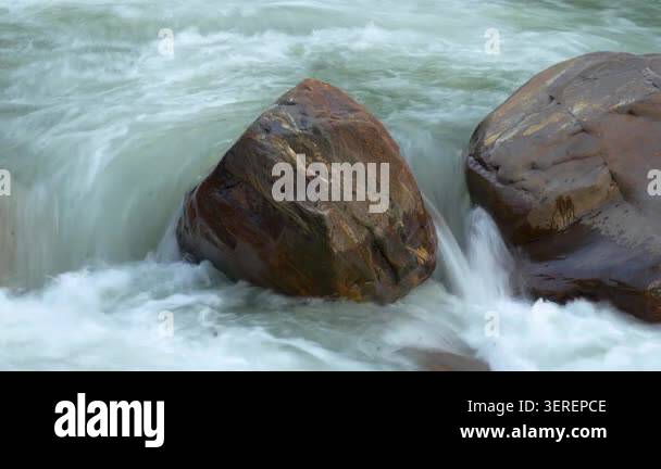A close-up of a fast-flowing river with large rocks, capturing the ...