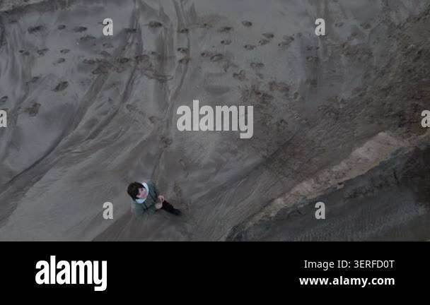 Aerial view of a person standing on a sandy beach with footprints ...