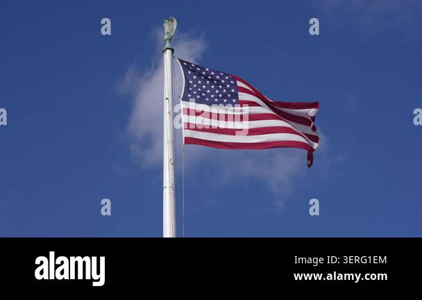 American Flag Waving On Tall Flagpole USA Flag Against Blue Sky Clouds American Flag Waving On Tall Flagpole USA Flag Against Blue Sky Clouds