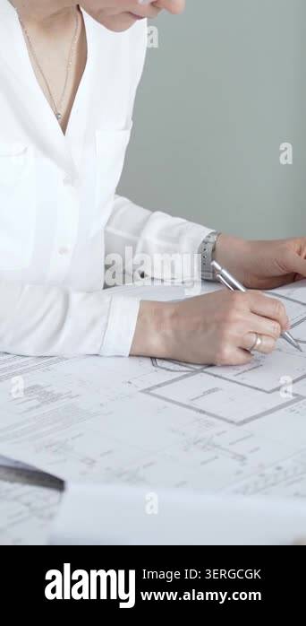 Professional female architect engrossed in reviewing blueprints and ...
