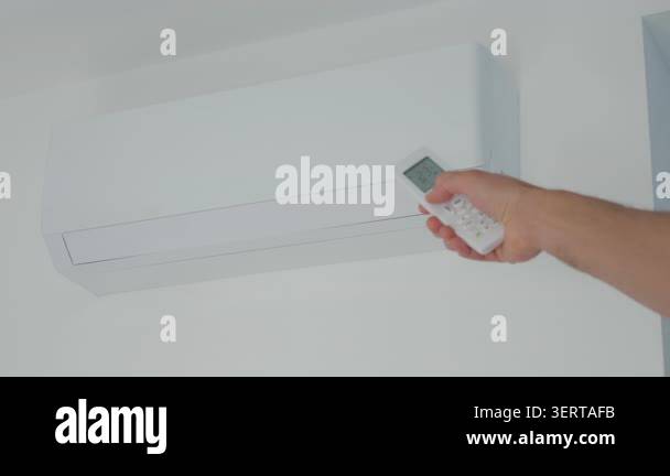 Hand adjusts air conditioner with remote control, setting temperature ...