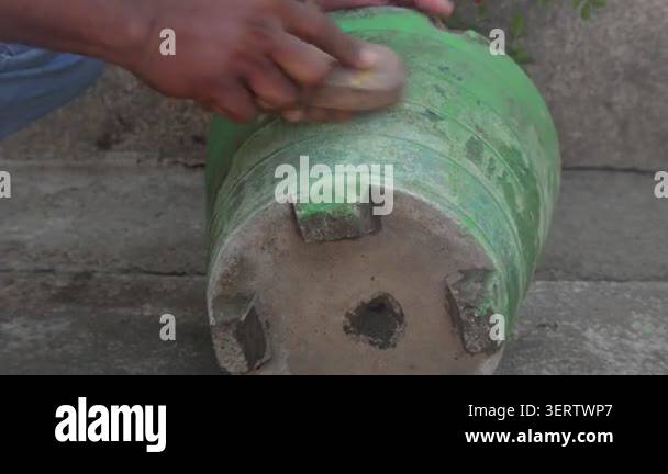 a-person-is-cleaning-a-green-cement-flowerpot-by-hand-using-a-coconut