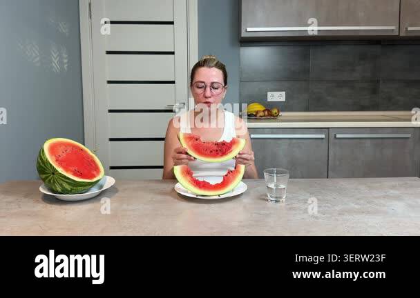 A Woman With Glasses And Hair Pulled Back Sits At A Modern Kitchen a-woman-with-glasses-and-hair-pulled-back-sits-at-a-modern-kitchen
