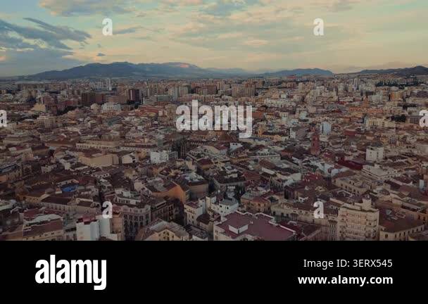 Drone flight above Malaga at sunset featuring the historic city center ...