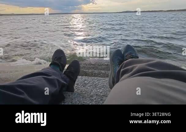 Female And Male Legs In Trousers And Feet On A Beach Against The Sea At female-and-male-legs-in-trousers-and-feet-on-a-beach-against-the-sea-at