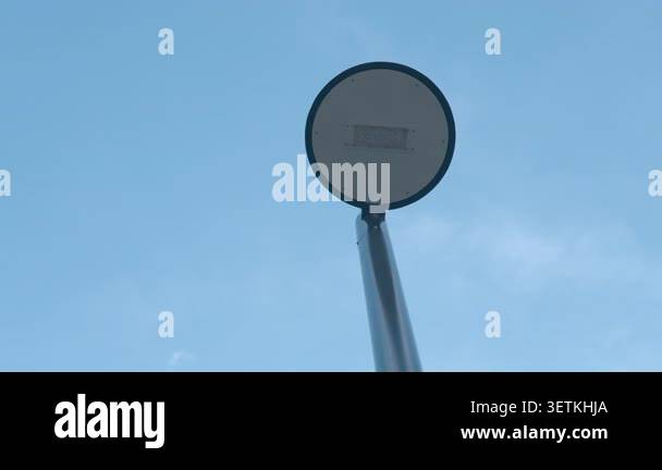 A simple round street sign mounted on a pole is viewed from below ...