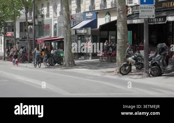PARIS, FRANCE, JUNE 4, 2026 People walk on a busy city sidewalk past ...