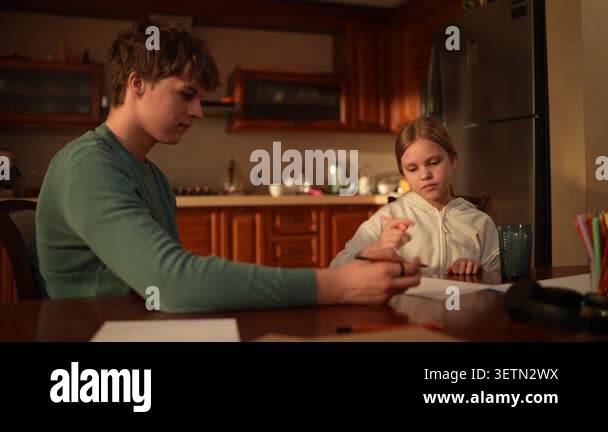 A father and daughter sit at the kitchen table and share time while ...