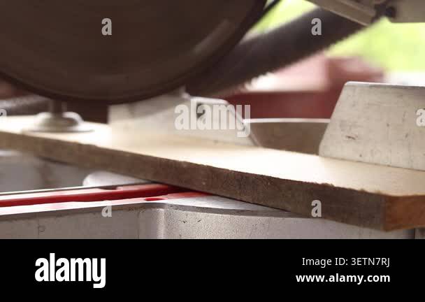 The process of sawing a wooden block with a miter saw. Close-up of the ...