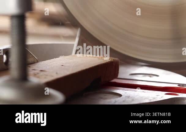 The process of sawing a wooden block with a miter saw. Close-up of the ...