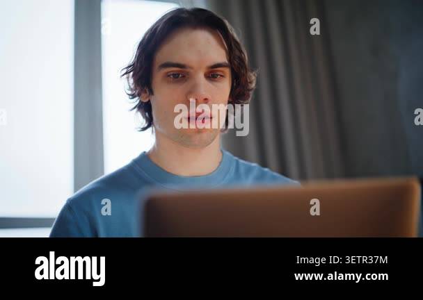 Portrait student working laptop at windows light room. Smiling man ...