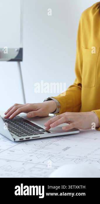 Woman architect actively working on a laptop computer, surrounded by ...