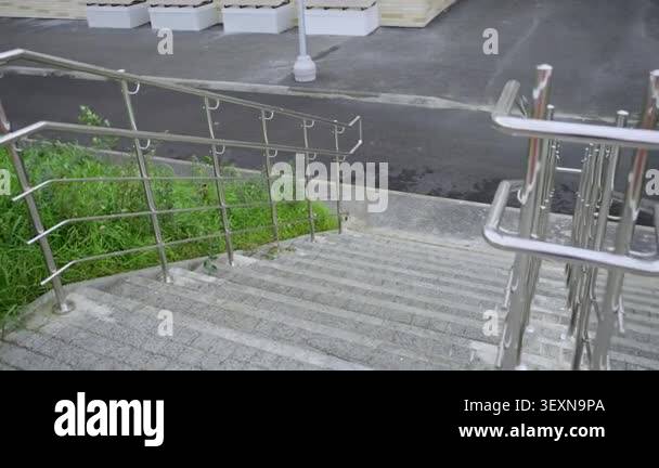 Stone stairs with stainless steel railings lead down to asphalt road ...
