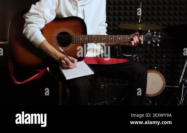 Young musician man making notes for writing new melody in recording ...