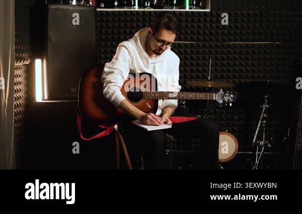 Young musician man making notes for writing new melody in recording ...