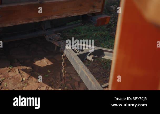 Close-up shot of a wooden trailer hitch with a chain. Metal parts show ...