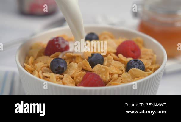 Fresh milk pouring with splash into cornflakes with raspberry and ...