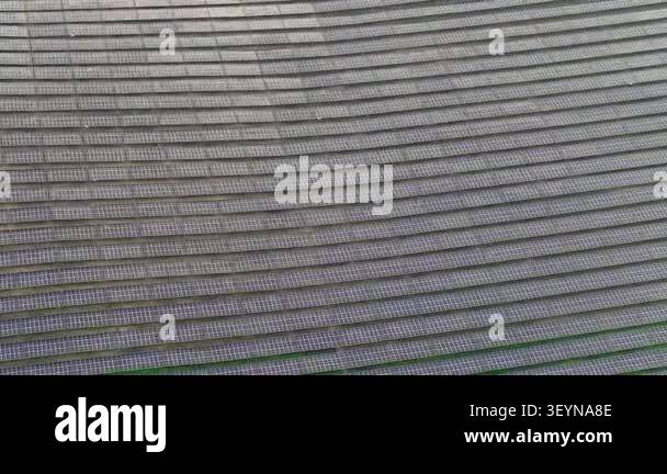 Aerial drone footage showing rows of ground-mounted solar panels at a ...