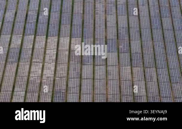 Aerial footage of rows of ground-mounted solar panels in a photovoltaic ...