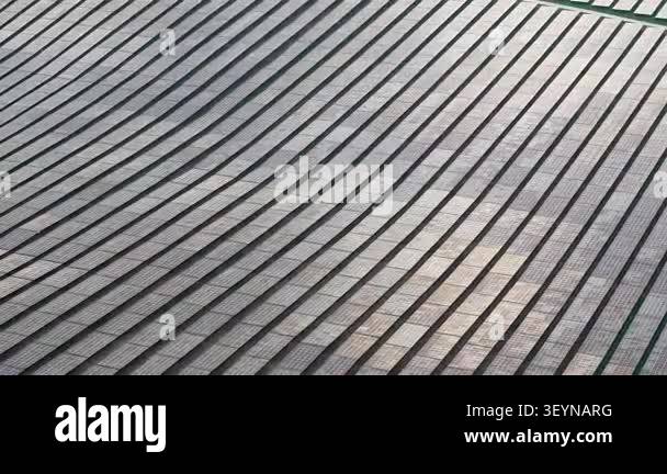 Aerial footage of ground-mounted photovoltaic solar panel farm showing ...