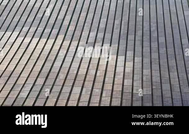 Aerial drone footage showing rows of ground-mounted solar panels in a ...
