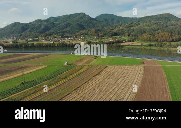 Solar panels stretch along a riverbank, producing clean energy in a ...