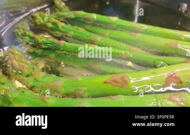 Fresh green asparagus spears boiling in water, showing gradual cooking ...