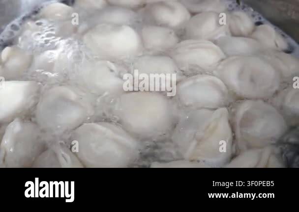 Boiling dumplings in a pot with bubbling water, showcasing the cooking ...
