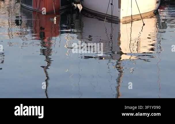 Colorful boat reflections create abstract patterns on the calm water ...