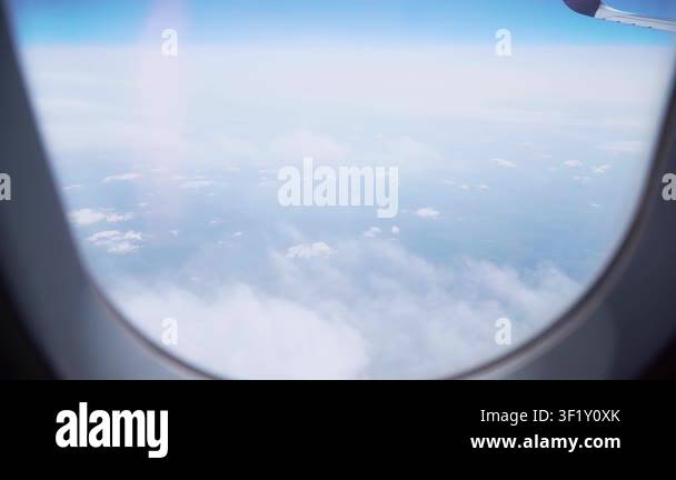 Airplane flying above clouds with view through passenger window and