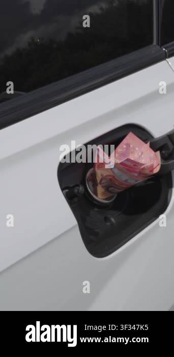 Close-up of female hand inserting euro cash into open fuel tank of ...