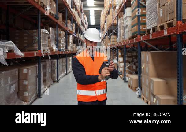 Young male worker managing inventory in a large distribution center ...