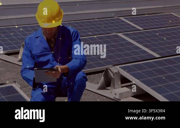 Tech kneeling by solar panels tapping tablet starting panel tests while ...