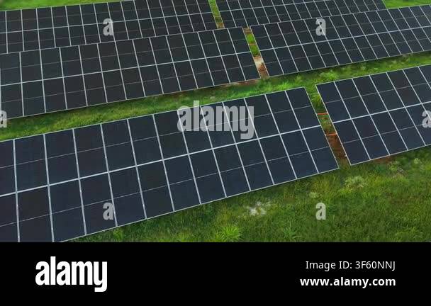 Overhead drone view of organized photovoltaic panel arrays across green ...