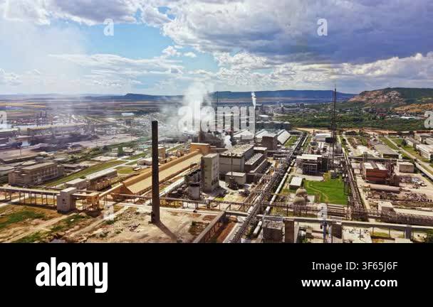 Industrial buildings and smokestacks fill the landscape. Smoke rises ...