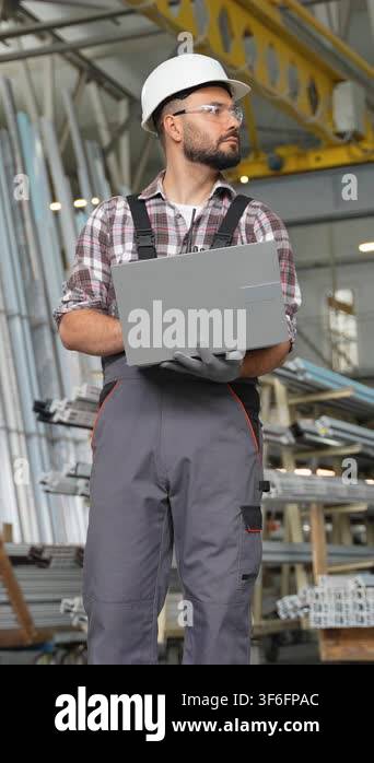Male worker in a hard hat and safety glasses using a laptop for ...