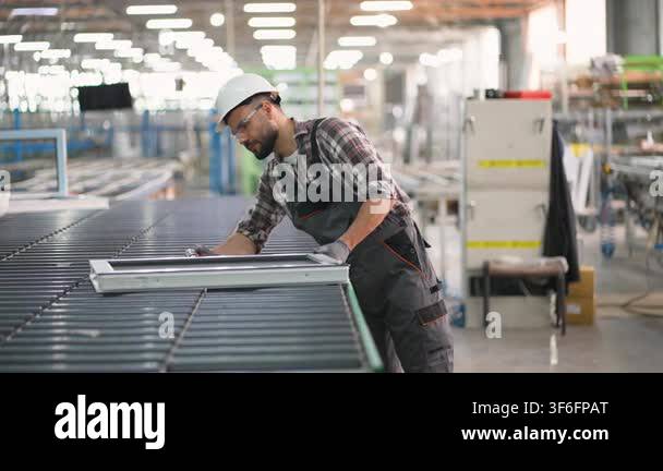 Focused male worker in a hard hat and protective glasses assembling a ...