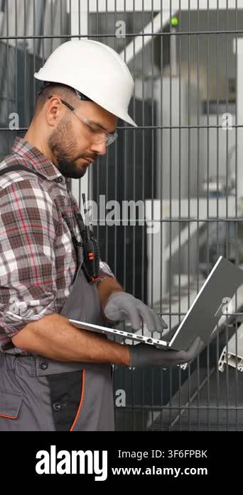 Professional engineer wearing a hard hat and safety glasses using a ...