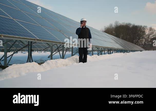 Male technician in a hard hat talking on a mobile phone while ...