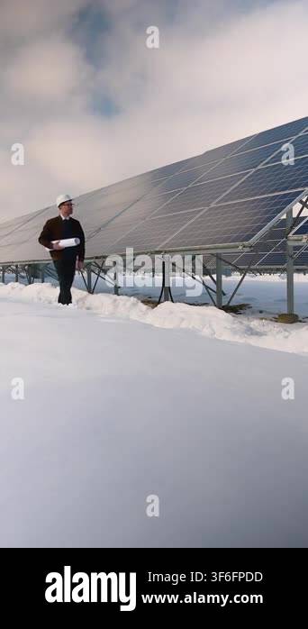 Male engineer wearing a hard hat and holding blueprints walks through ...
