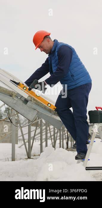 Male engineer in a hard hat installing and adjusting photovoltaic solar ...