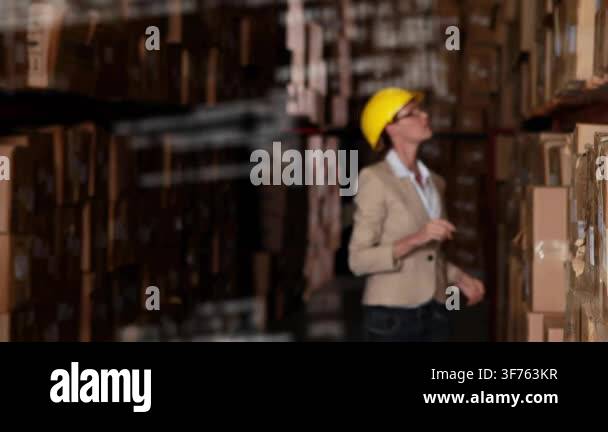 Warehouse inspector reaching upper shelf, scanning box labels, checking ...
