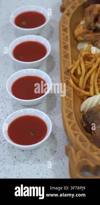 Slow motion camera panning of red tomato dipping sauces in small white ...