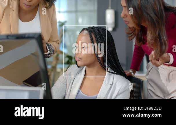 Seated woman gesturing at monitor, colleagues pointing, producing ...